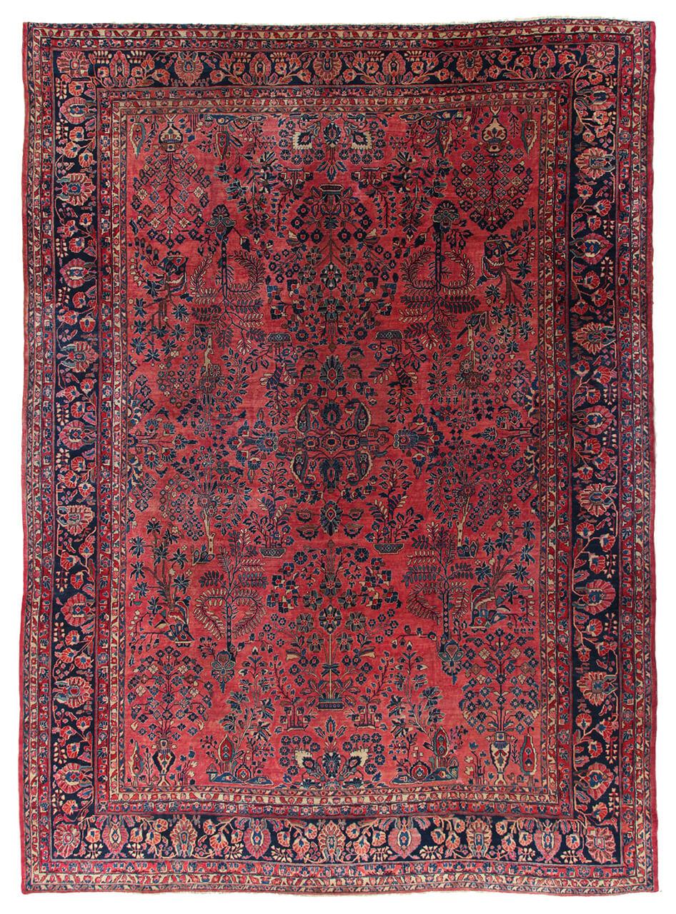 A large, rectangular antique Sarouk rug from the Middle East featuring a vibrant red field with intricate floral patterns and a dark border.