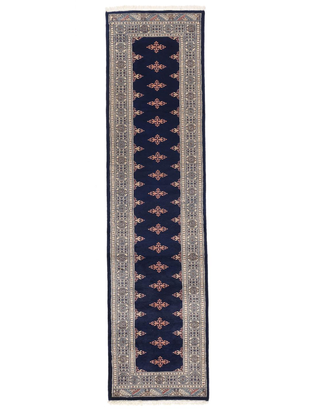 A long, narrow hand-knotted runner from Pakistan with a deep blue field and repeating motifs.