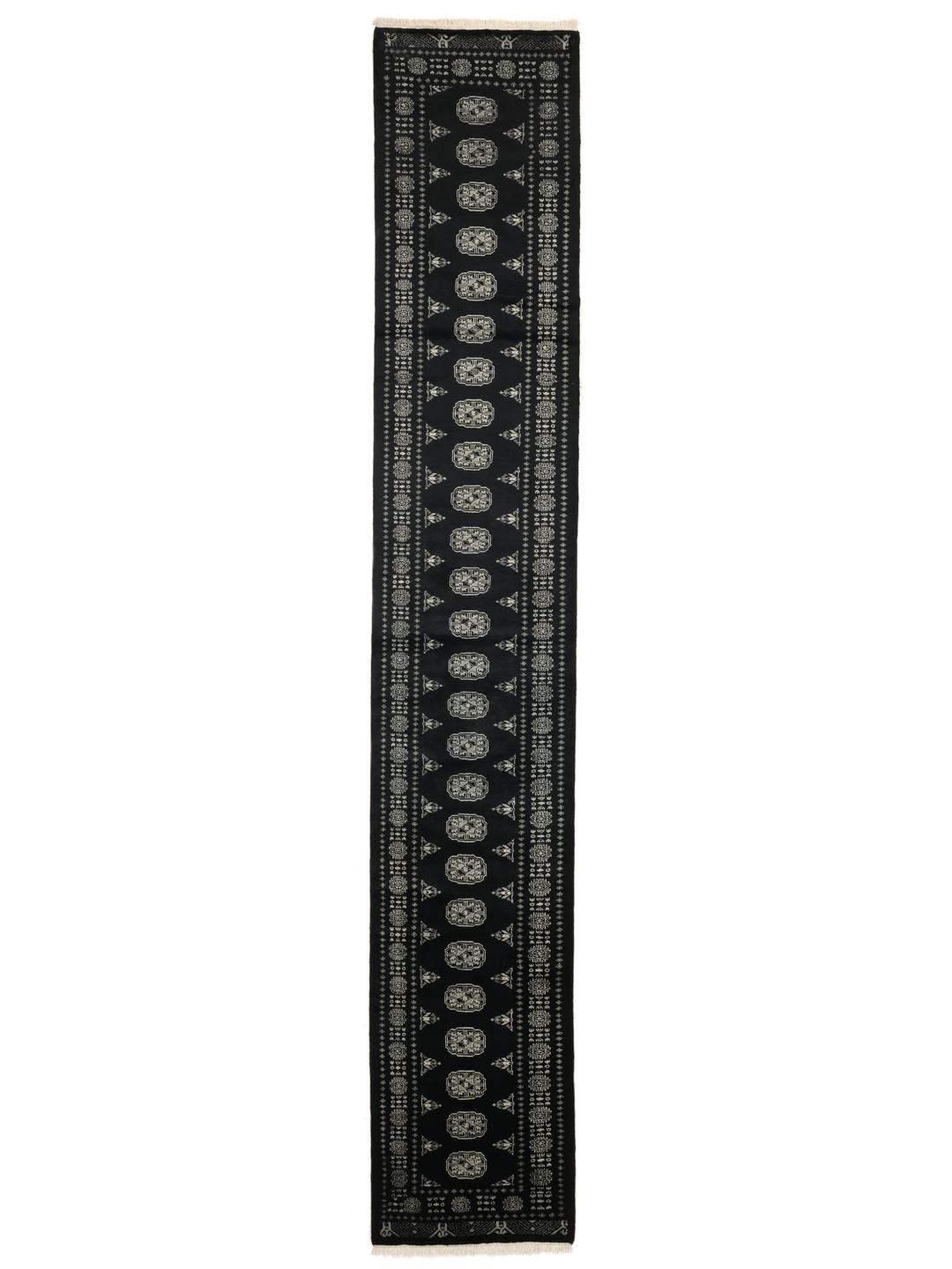 Un long tapis couloir noué à la main, de couleur noire, originaire du Pakistan avec des motifs répétitifs traditionnels.