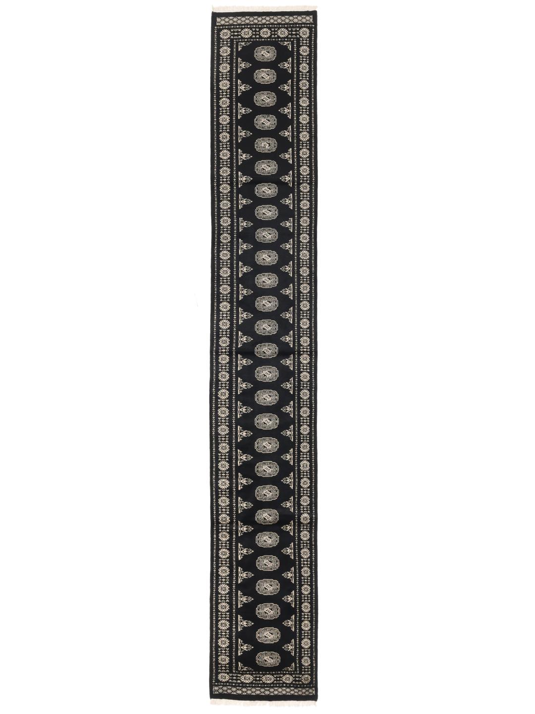 A long, black hand-knotted runner from Pakistan with traditional white motifs.