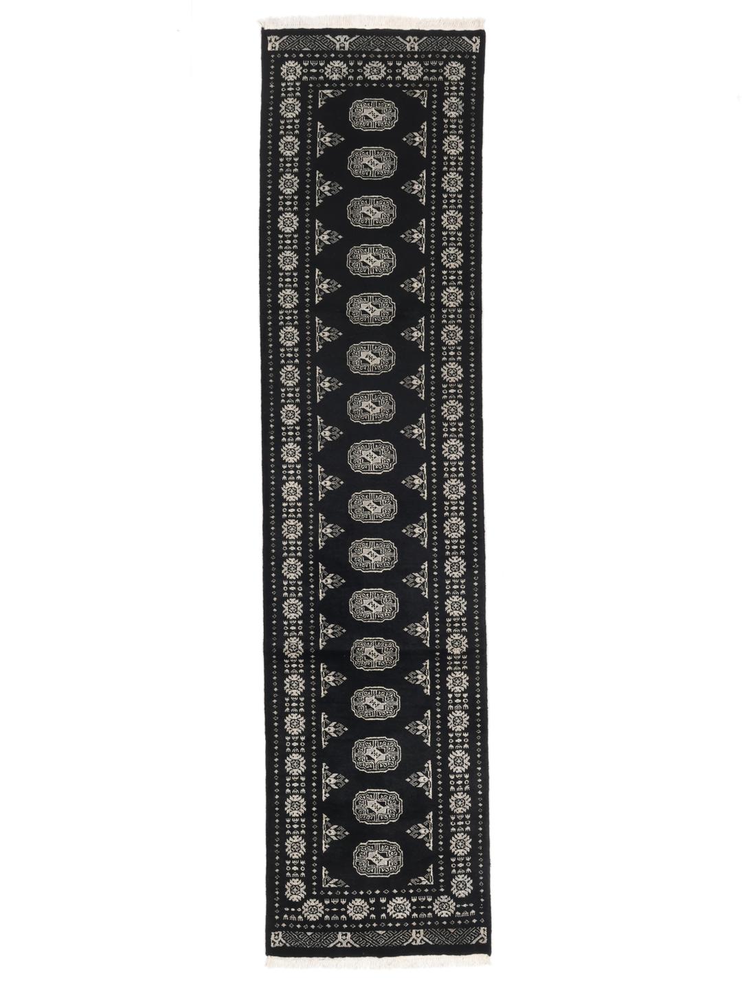 A long, hand-knotted runner from Pakistan with a black field and traditional patterns.