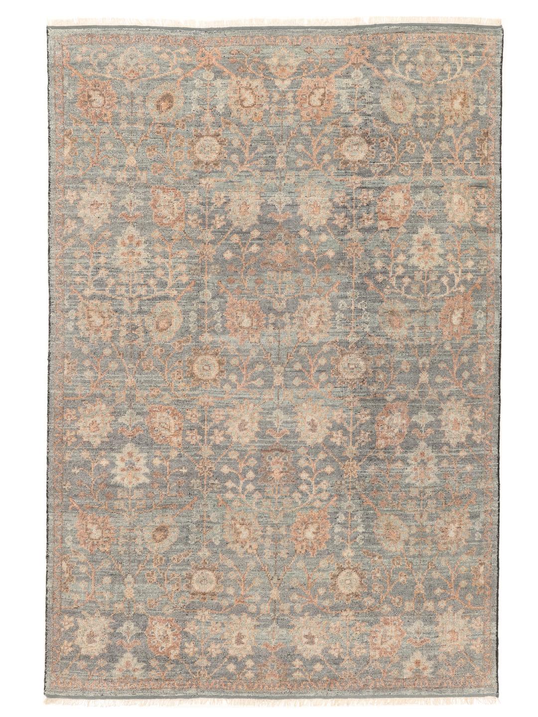 Een groot handgeknoopt Indiaas tapijt met een zacht blauw en perzikkleurig bloemenpatroon.
