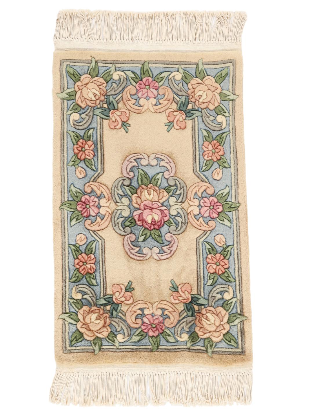 Et rektangulært tæppe fra Kina med blomstermønstre i beige, blå og lyserød.