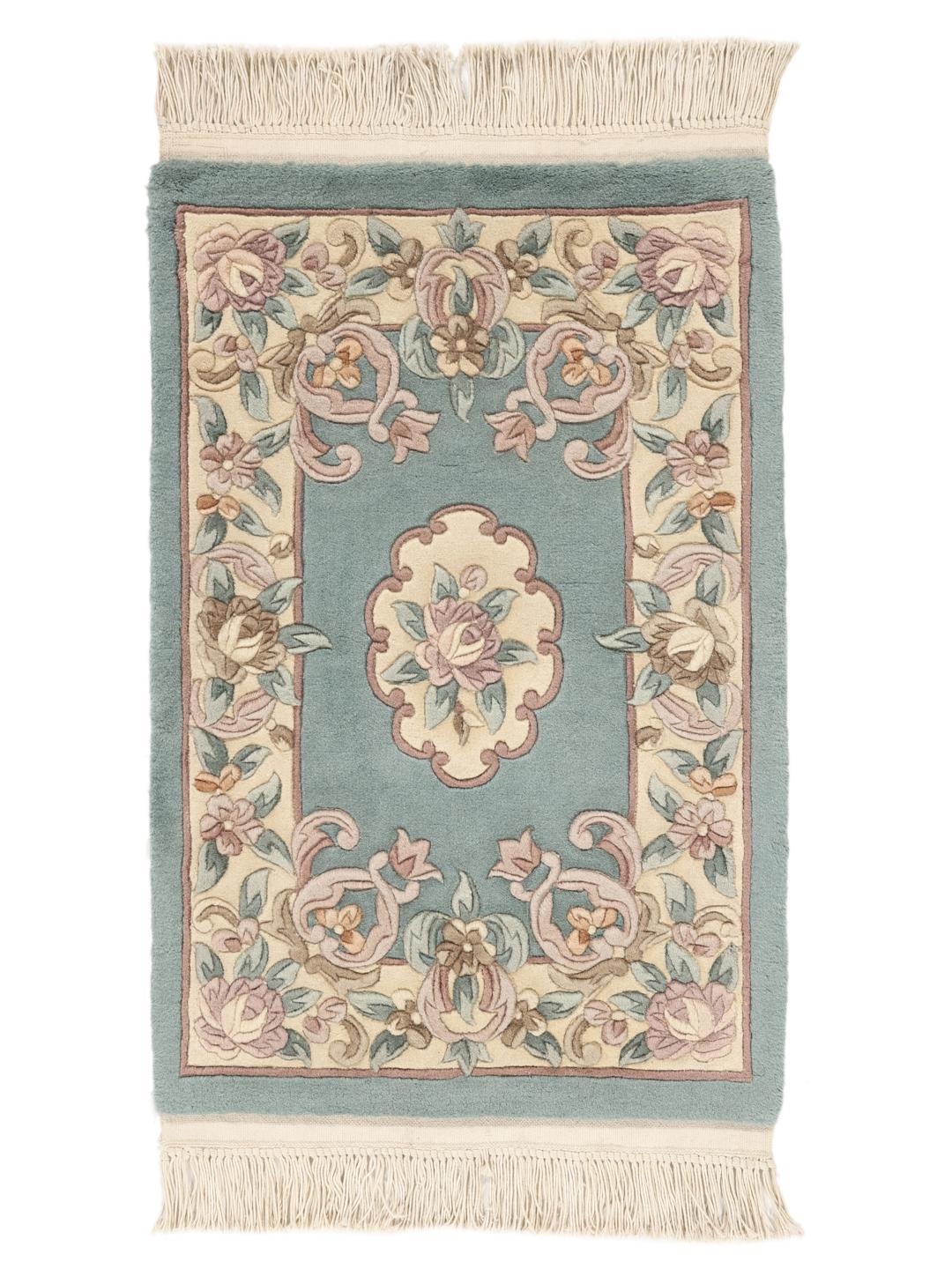 Et rektangulært håndknyttet tæppe fra Kina med et blomstermønster i lyseblå og beige.