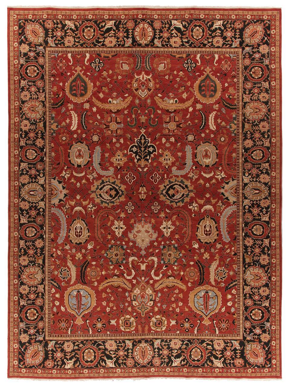 Una gran alfombra rectangular anudada a mano con un patrón tradicional floral y de medallón en rojo y negro, originaria de la India.