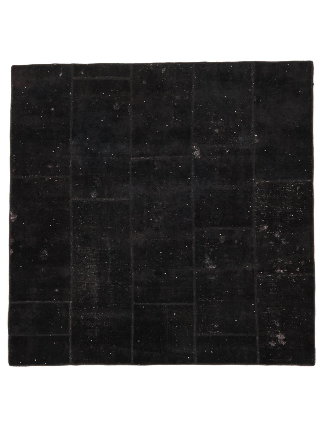 Een vierkant zwart patchwork tapijt met een textuurrijke, moderne afwerking.