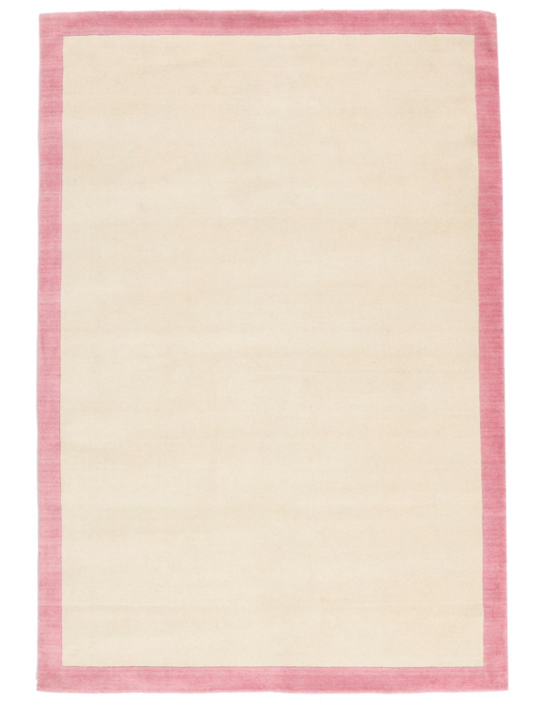 Et minimalistisk håndvævet tæppe fra Indien med beige center og pink kant