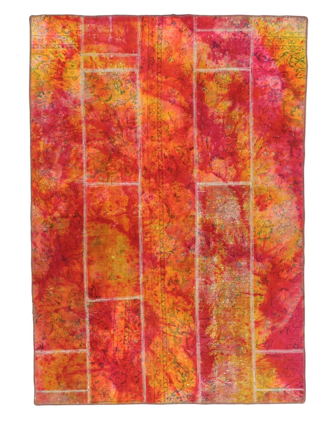 Un tapis patchwork rectangulaire vibrant provenant du Moyen-Orient, présentant un mélange de motifs floraux rouges et orange.