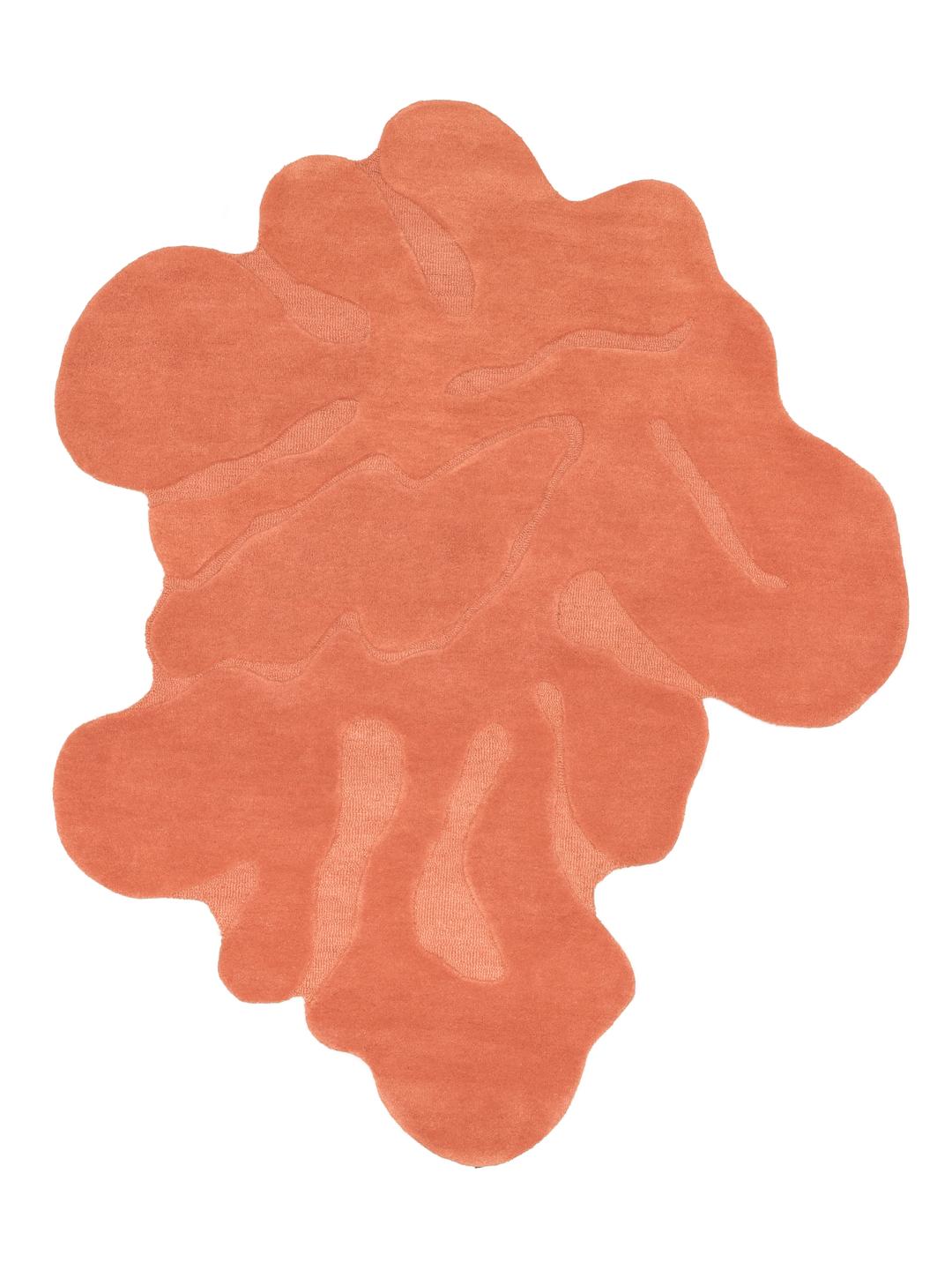 Handgemaakt oranje tapijt met een organische vorm en zachte wollen pool.