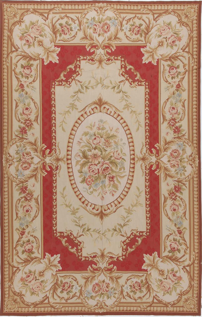 Et rektangulært håndvævet tæppe i Aubusson-stil med blomstermønstre i røde og beige toner.