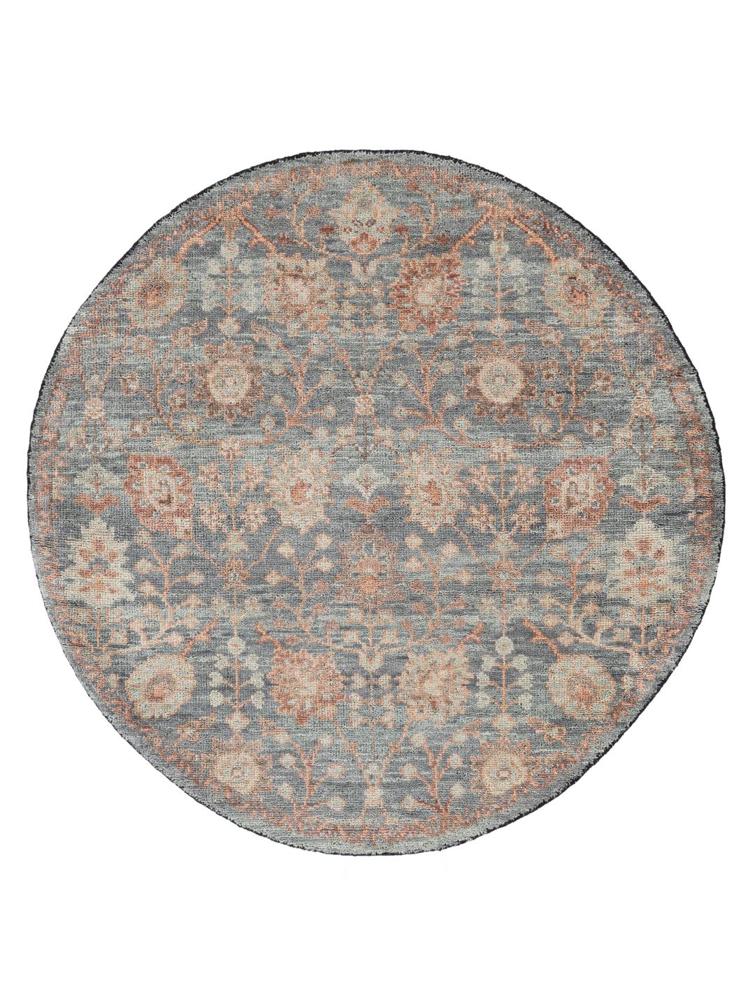 Una alfombra redonda de lana Usak Indo con diseño floral en tonos grises y apagados de la India