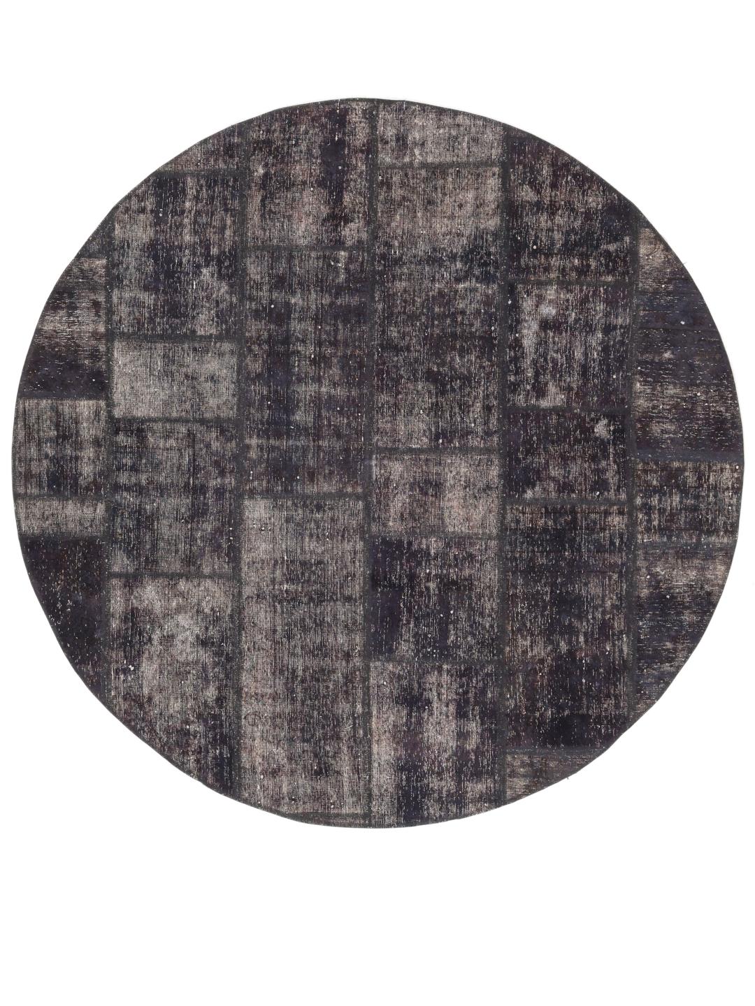 Een rond patchwork vloerkleed met een donkergrijze en zwarte verweerde uitstraling