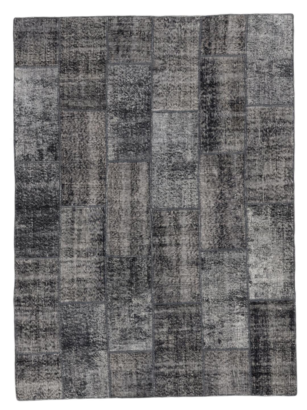 Een uniek, met de hand geknoopt patchwork vloerkleed uit Turkije in verschillende tinten donkergrijs.