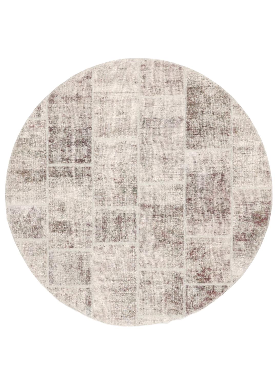 Een rond patchworktapijt in tinten beige en lichtbruin met een textuurrijk oppervlak.