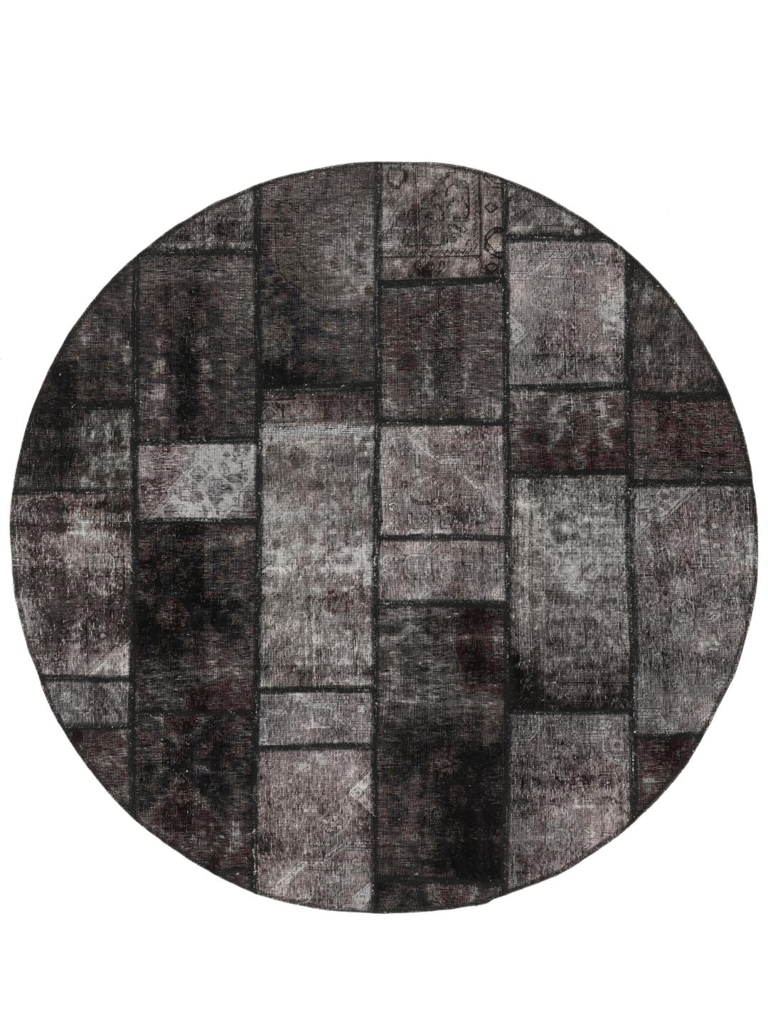 Et rundt patchwork-tæppe i en mørkegrå og koksgrå farvepalette med varierede geometriske teksturer.