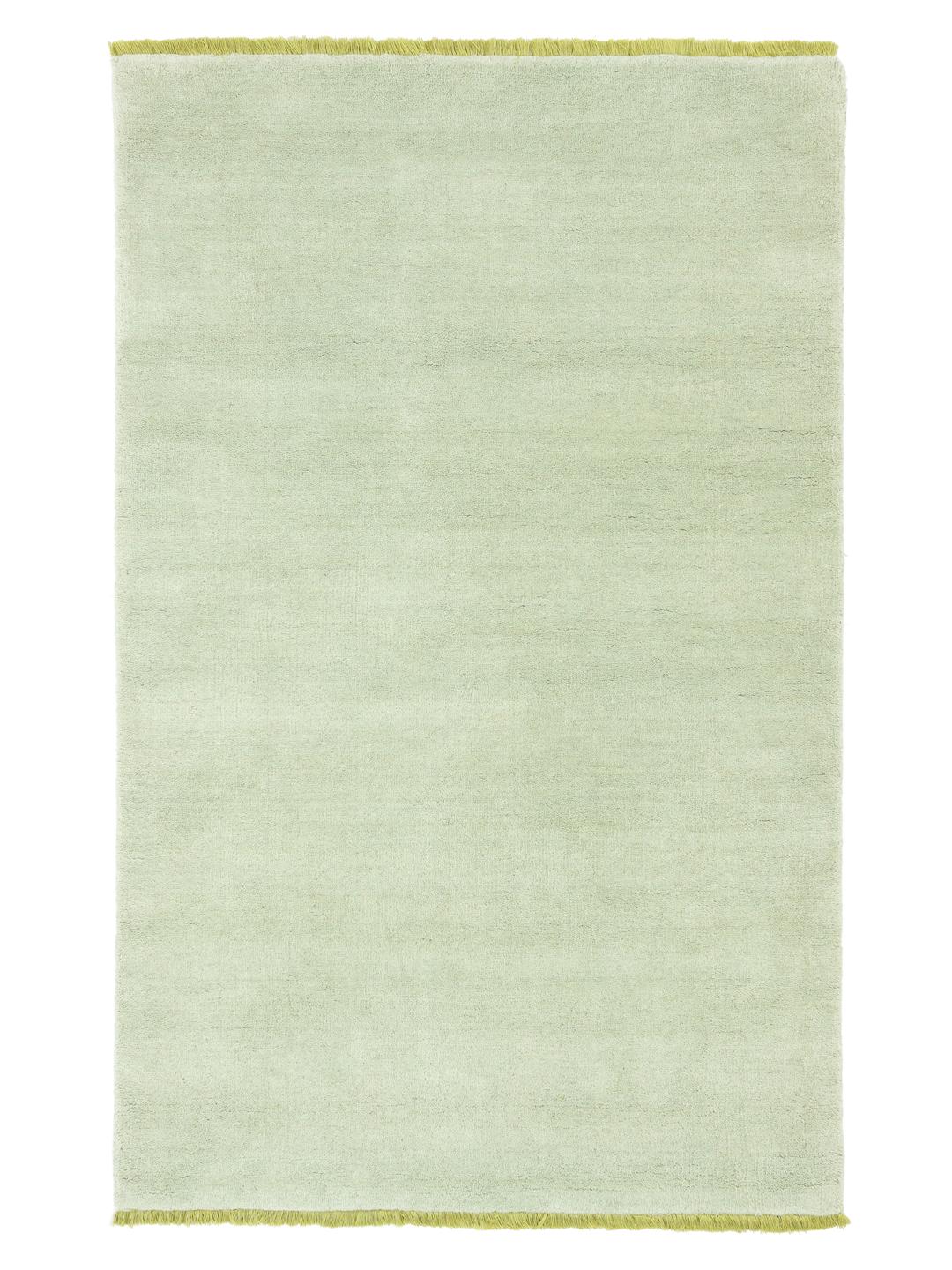 Een handgeweven tapijt in een zachte mintgroene kleur met decoratieve franjes.