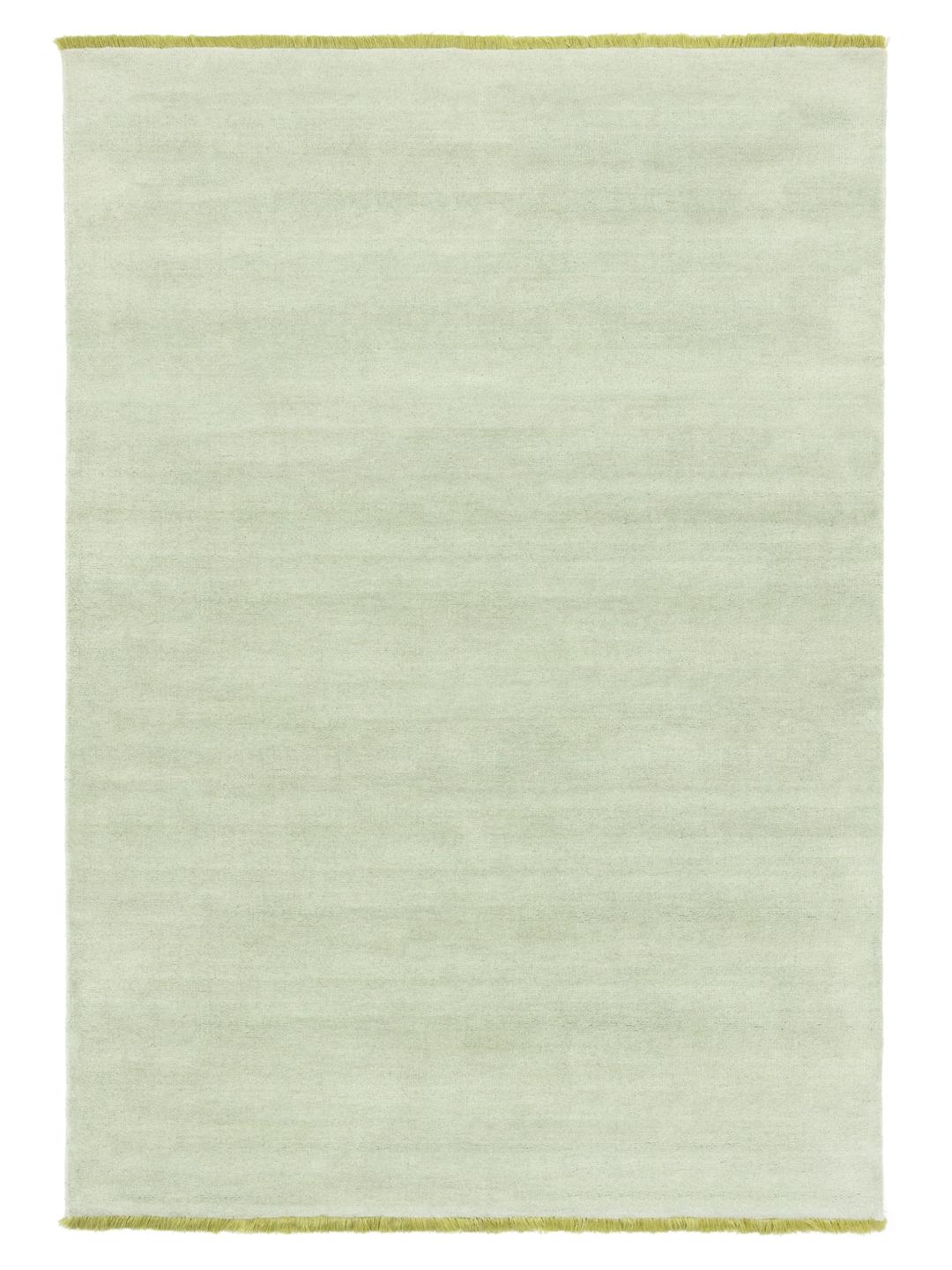 Een handgeweven tapijt in een zachte mintgroene kleur met decoratieve franjes.