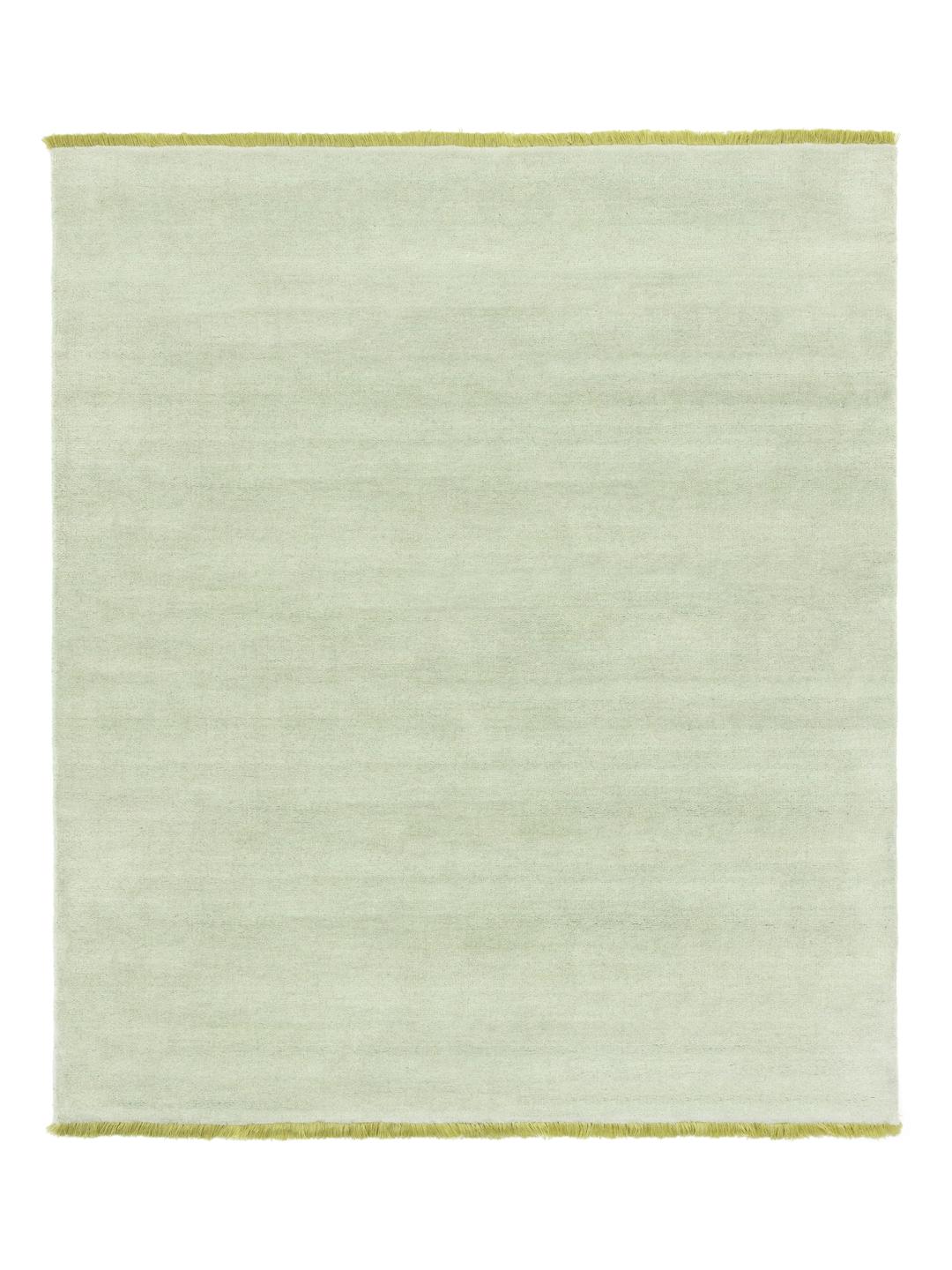 Een handgeweven tapijt in een zachte mintgroene kleur met decoratieve franjes.