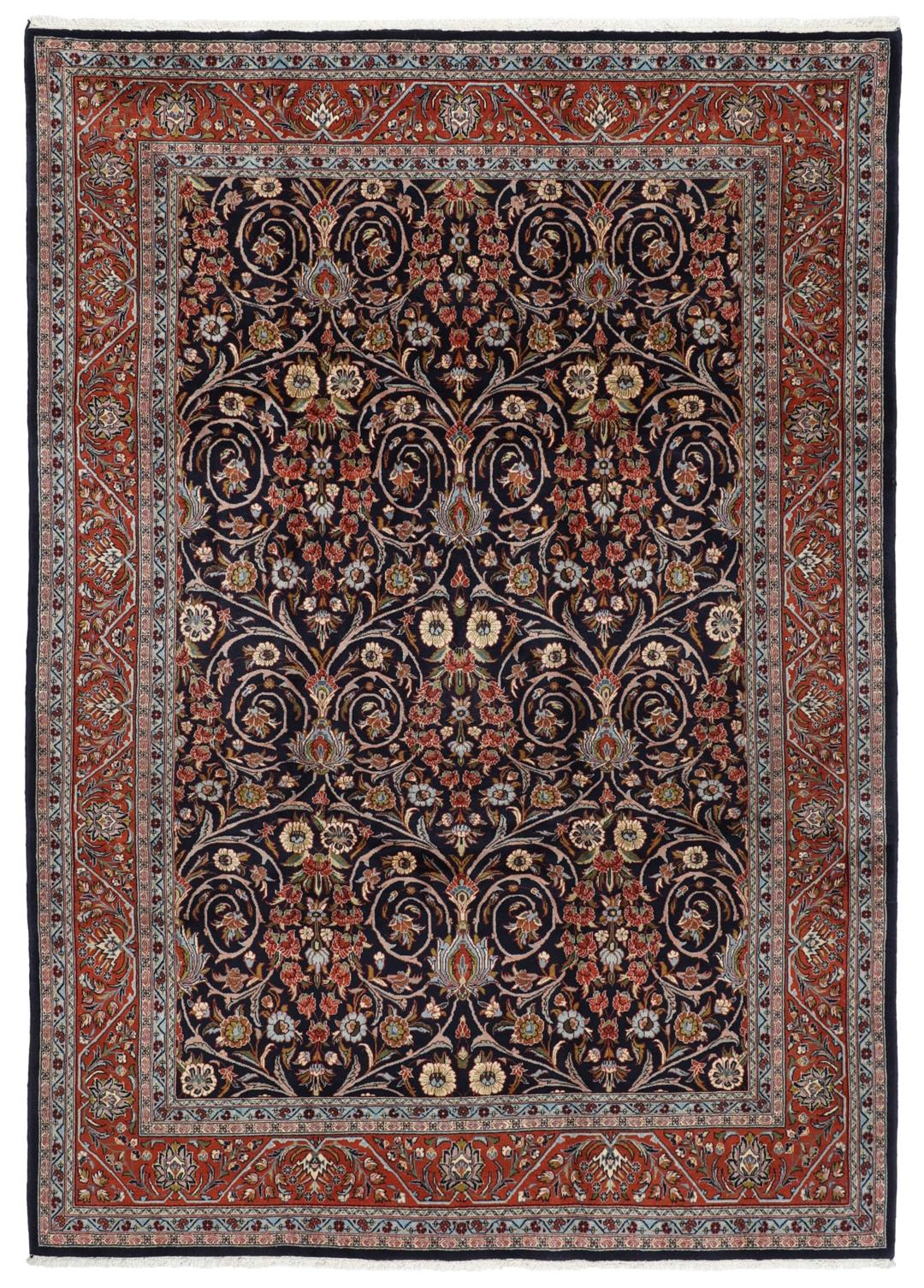 A large rectangular hand-knotted Sarough rug from the Middle East with a dark-blue field and floral patterns.