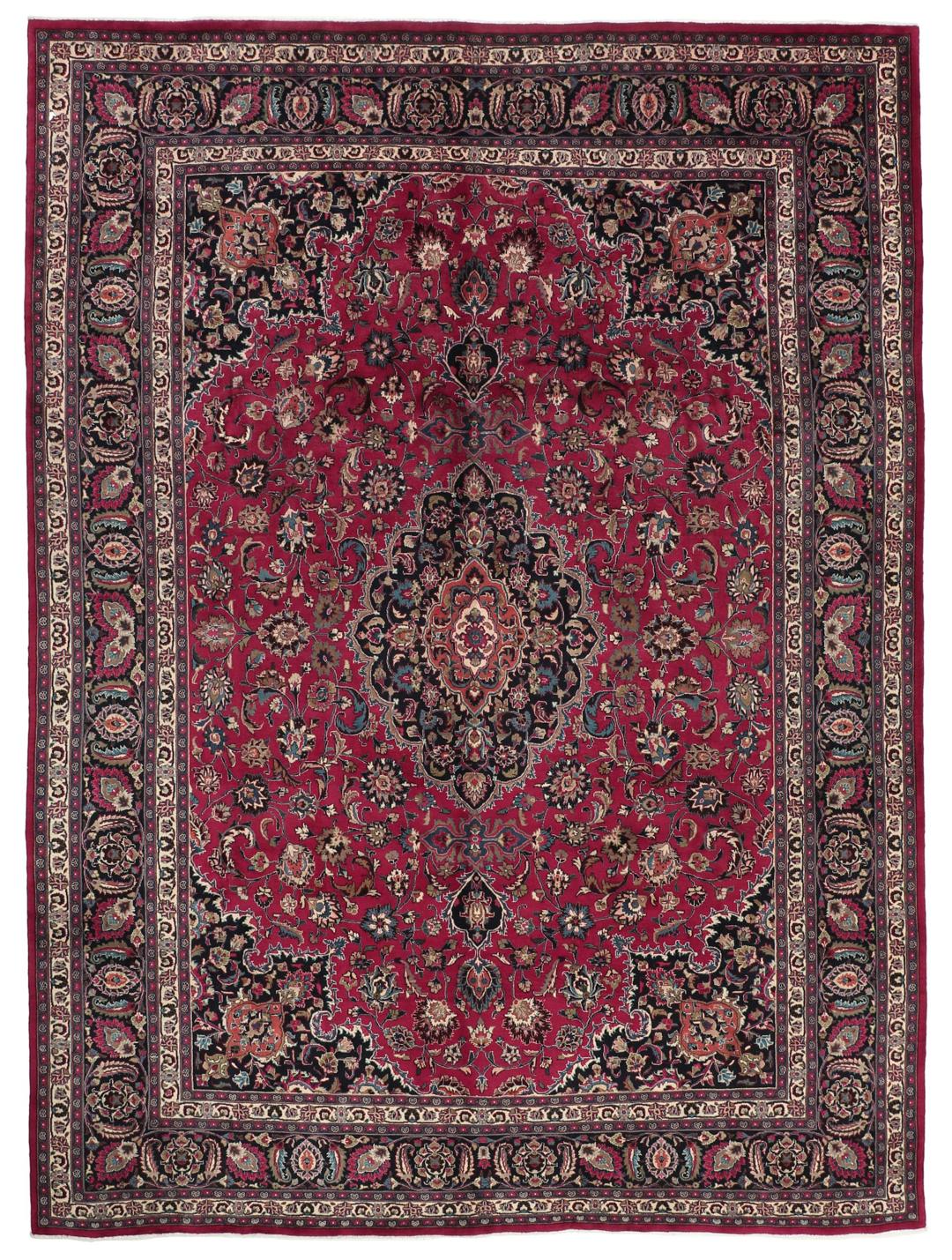 A large, hand-knotted Mashad rug from the Middle East with a deep red field and floral motifs.