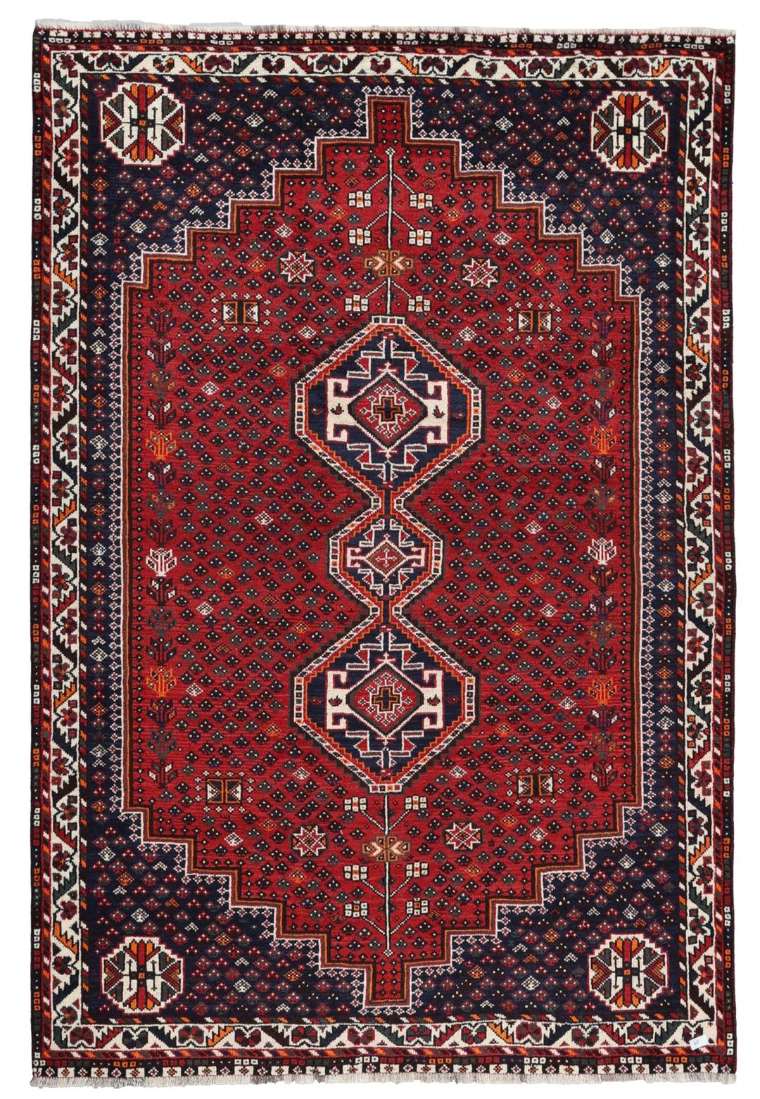 Een handgeknoopt rood Shiraz-tapijt met geometrische patronen en een decoratieve rand.