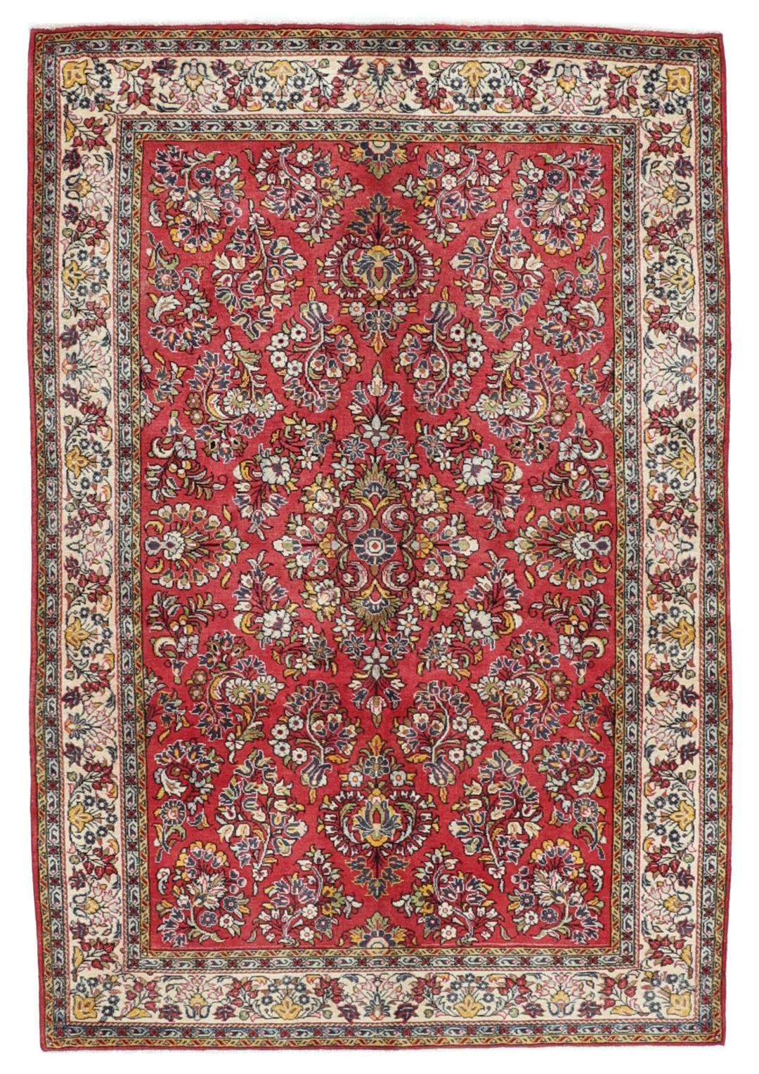 A hand-knotted Sarough rug from the Middle East featuring a vibrant red field and intricate floral patterns.
