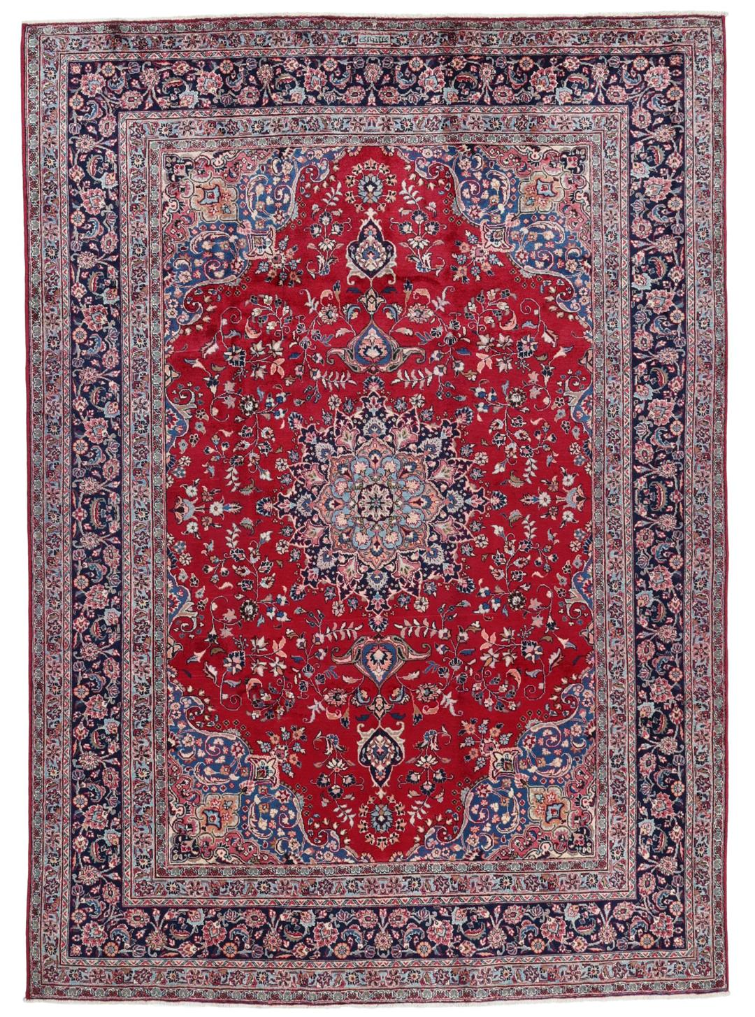 Un tapis Mashad noué main en provenance du Moyen-Orient avec un champ rouge et un motif de médaillon traditionnel.