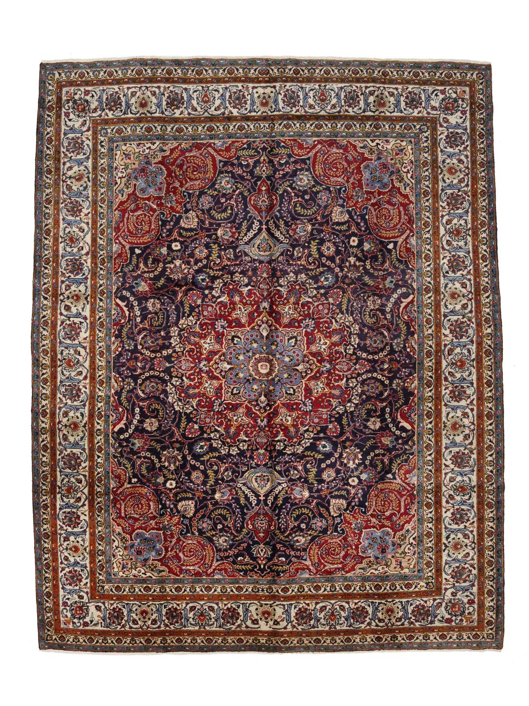 A large, hand-knotted Mashad rug from the Middle East with a dark-blue field and ornate floral medallion in shades of red and blue.