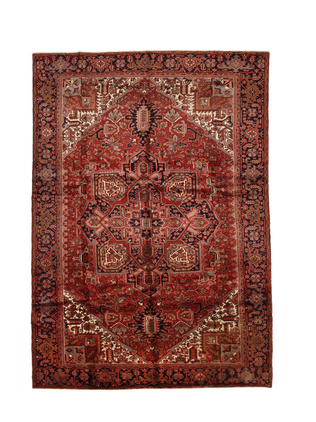 A hand-knotted Heriz rug from the Middle East with a striking red field and intricate geometric medallion.