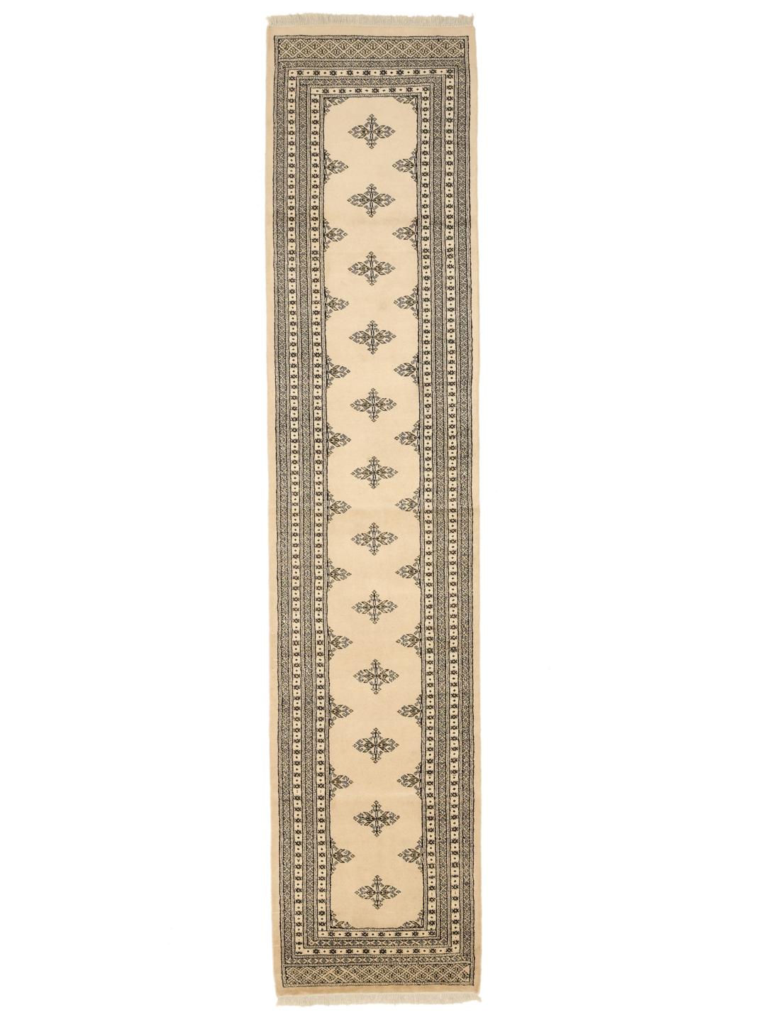 A long, beige hand-knotted runner from Pakistan with black repeating motifs.