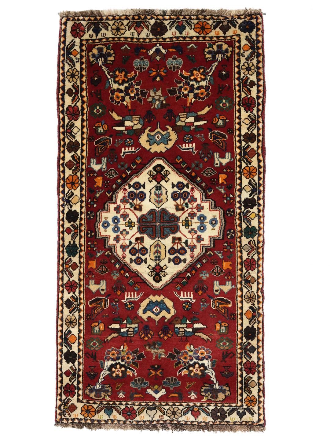 A vibrant red hand-knotted Shiraz rug with intricate geometric tribal patterns and a central medallion.