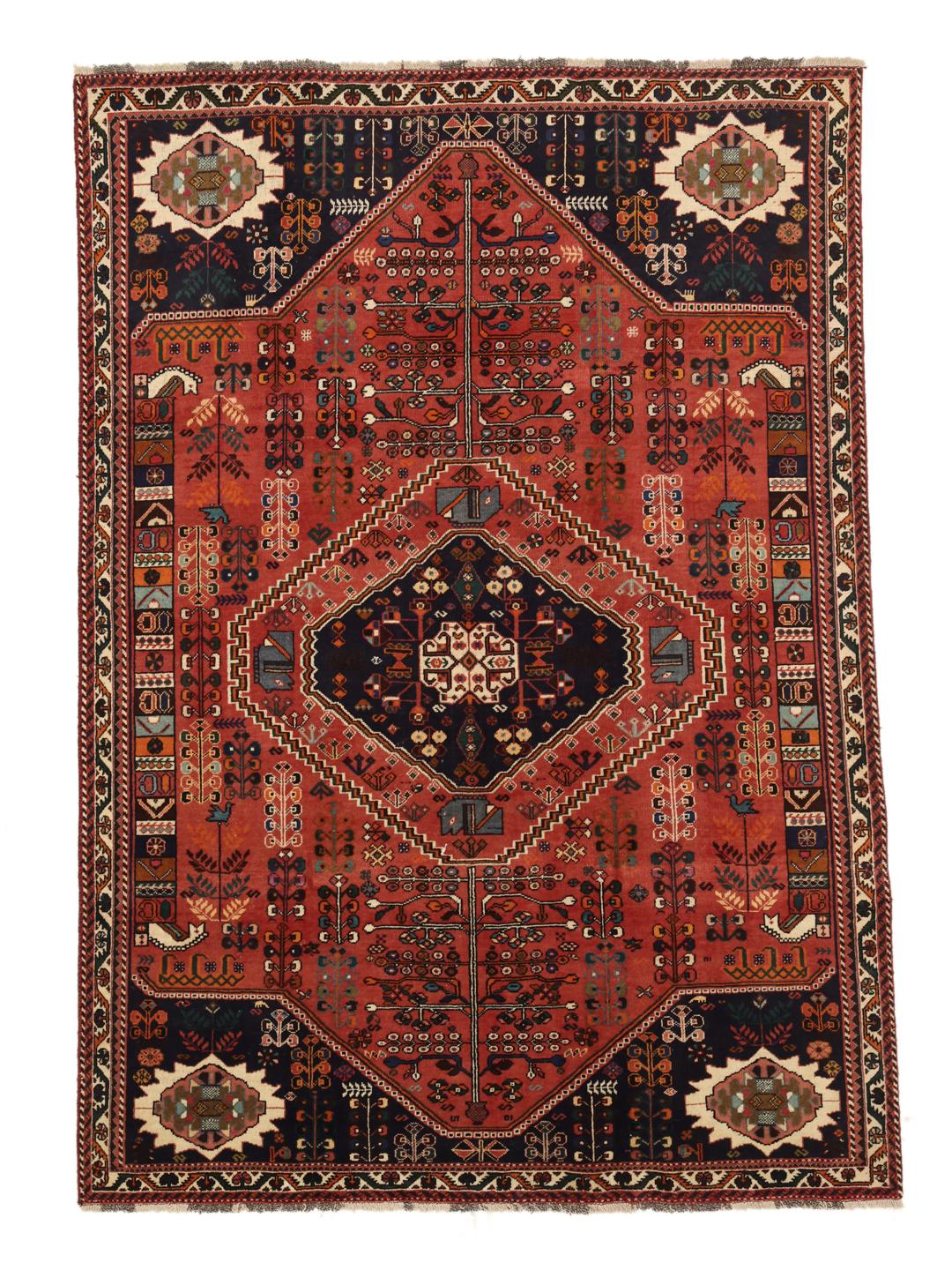 A hand-knotted Middle Eastern rug with a red field and traditional geometric patterns
