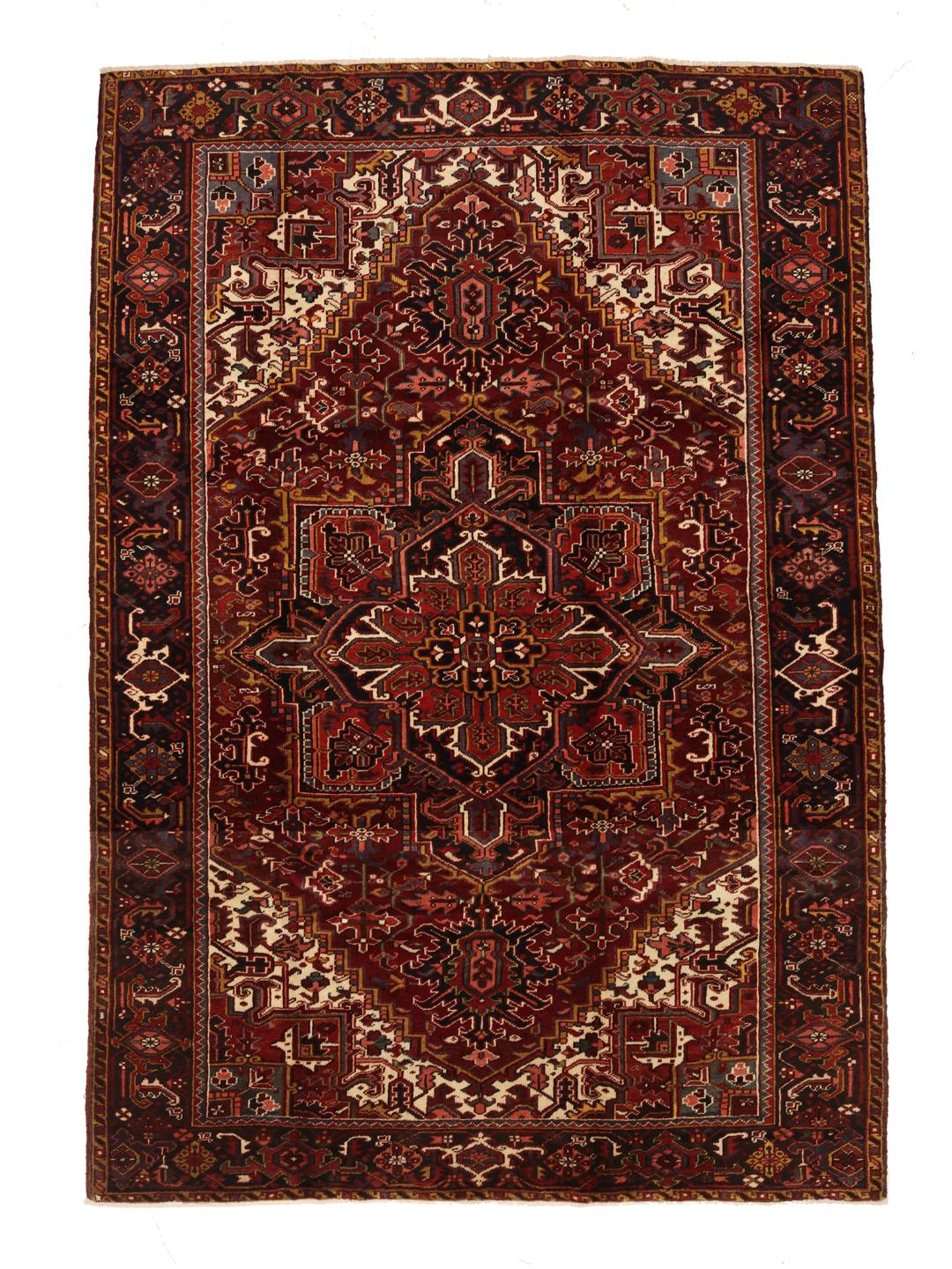 A hand-knotted Heriz rug from the Middle East in deep red and dark blue tones.