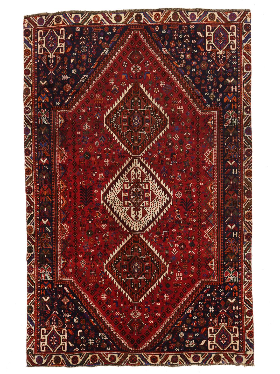 A hand-knotted Qashqai rug from the Middle East featuring a vibrant red and navy blue geometric tribal pattern.