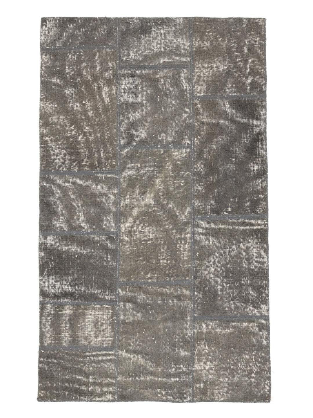 Et rektangulært patchwork-tæppe fra Mellemøsten i forskellige nuancer af mørkegrå.
