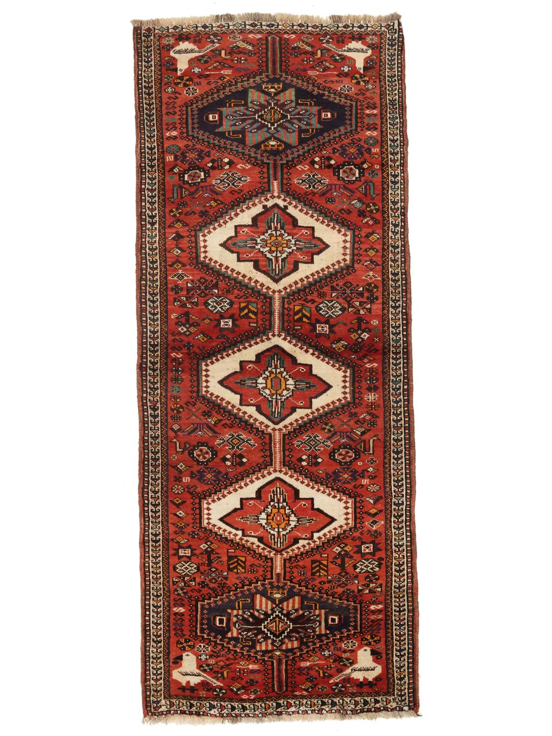 A hand-knotted Shiraz rug from the Middle East featuring a red field with geometric medallions.