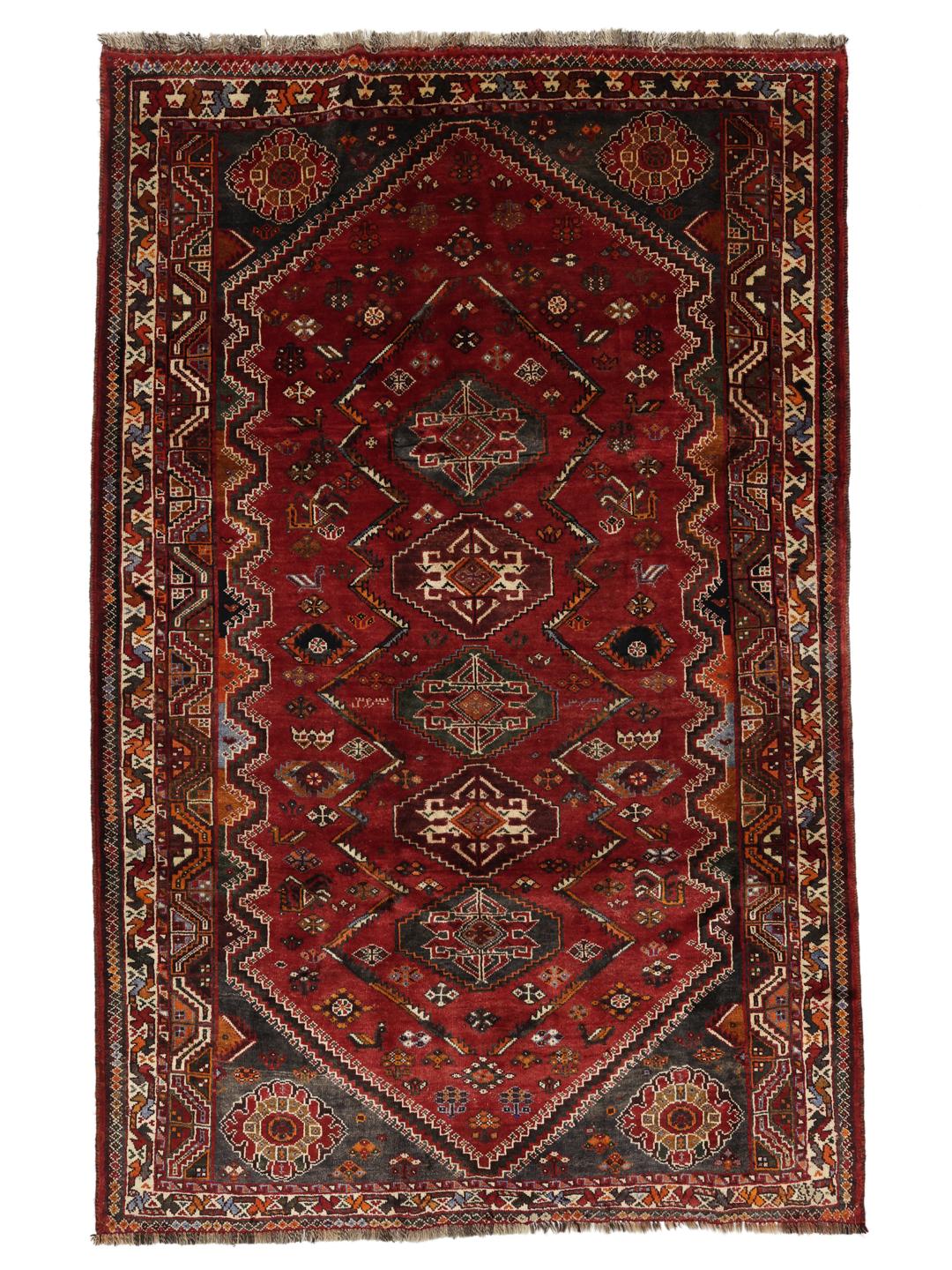 A hand-knotted Ghashghai rug from the Middle East featuring a vibrant red and dark-blue geometric design.