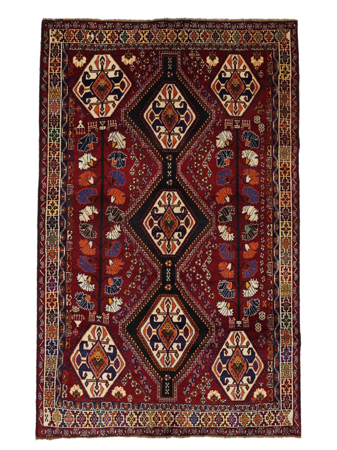A hand-knotted Qashqai rug from the Middle East featuring a vibrant red field and geometric medallion patterns.