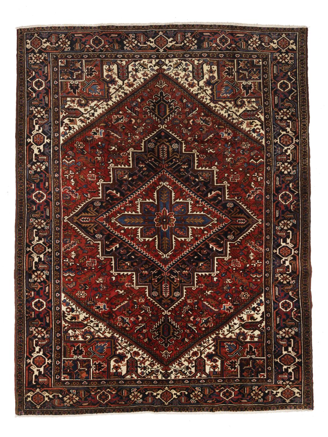 A hand-knotted Heriz rug from the Middle East featuring a vibrant red and blue geometric medallion design.
