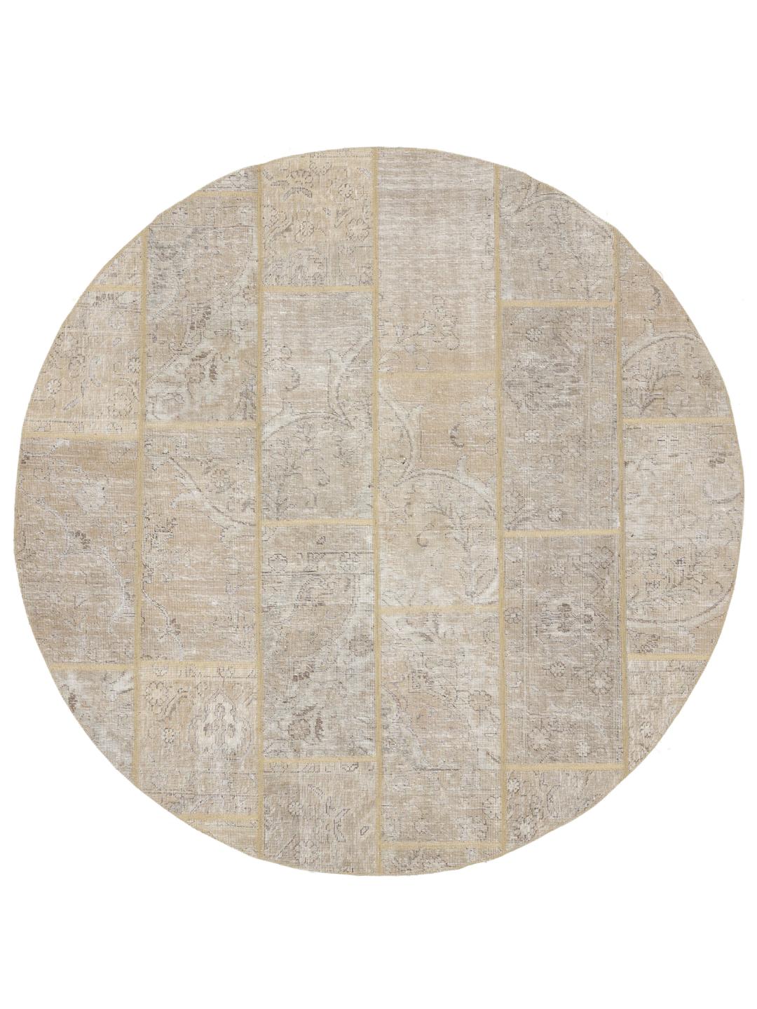 Et rundt beige patchworktæppe med dekorative mønstre og en slidt, vintage-inspireret finish.