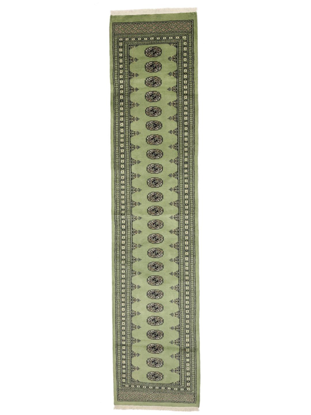 A long, hand-knotted runner from Pakistan with a green field and traditional patterns.