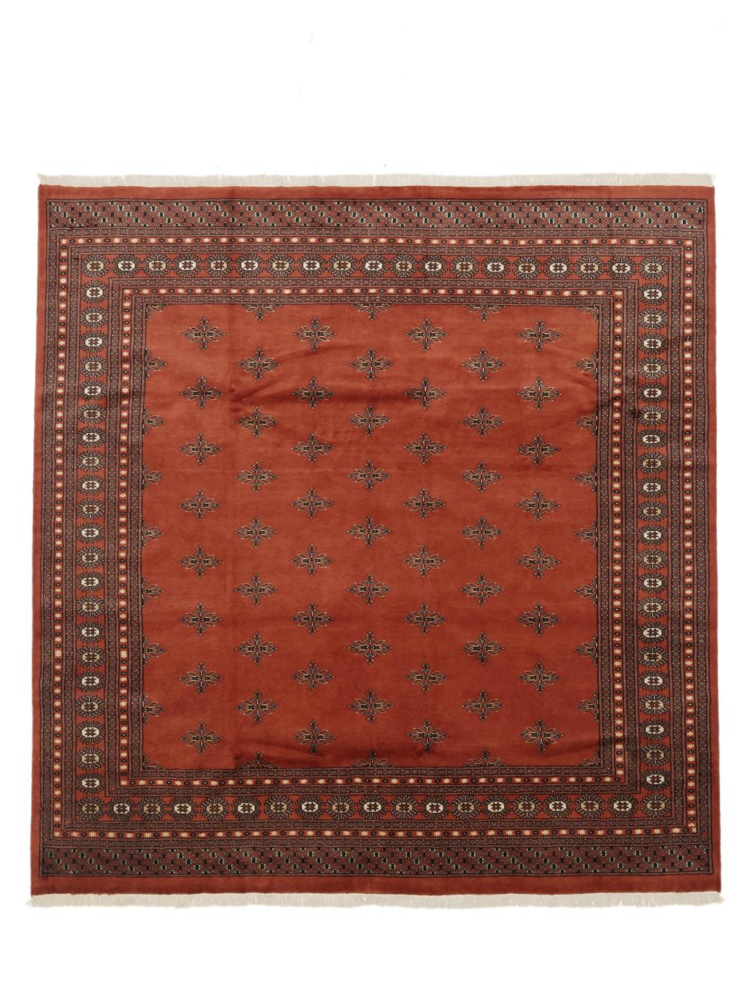 Een vierkant handgeknoopt Bokhara tapijt uit Pakistan met een dieprood veld en geometrische motieven.