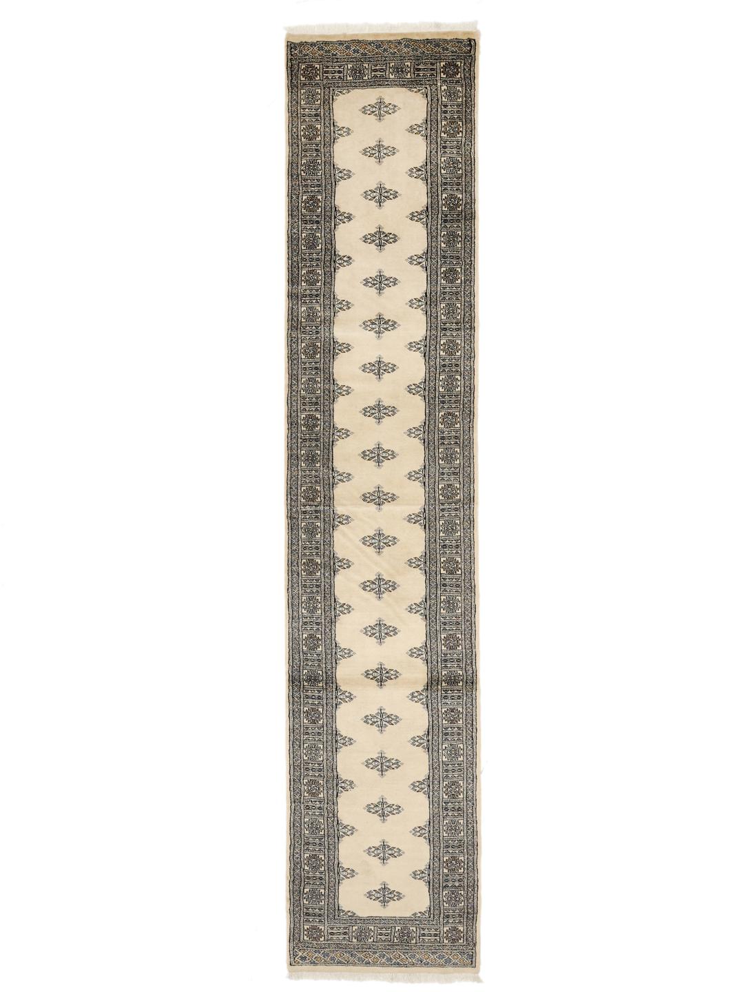 A long, cream-colored Pakistani hand-knotted runner with dark geometric motifs.