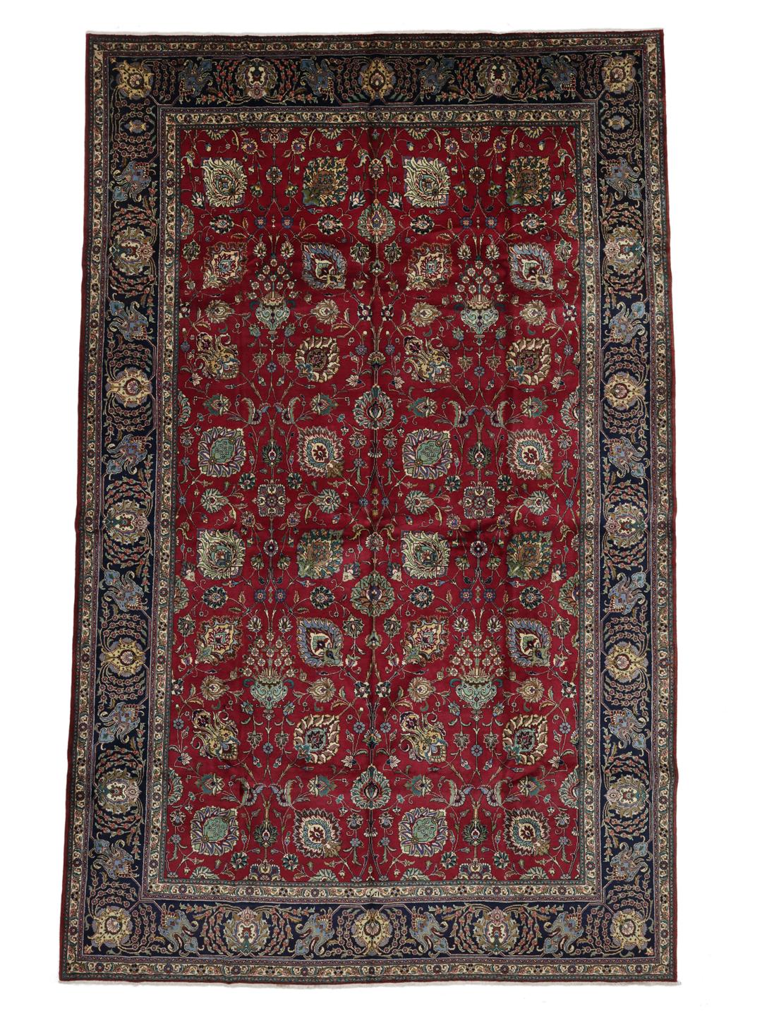 Een groot rechthoekig Tabriz-tapijt uit het Midden-Oosten met een rood veld en een blauwe rand.