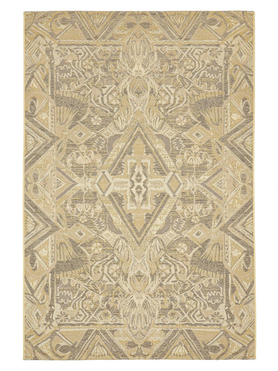 Et beige tæppe med et geometrisk stammeinspireret mønster